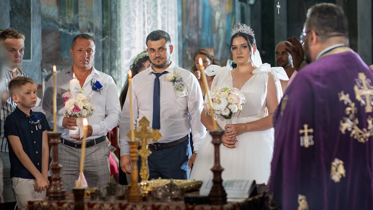 Bride and groom in an ornate church during a traditional wedding ceremony with candles.